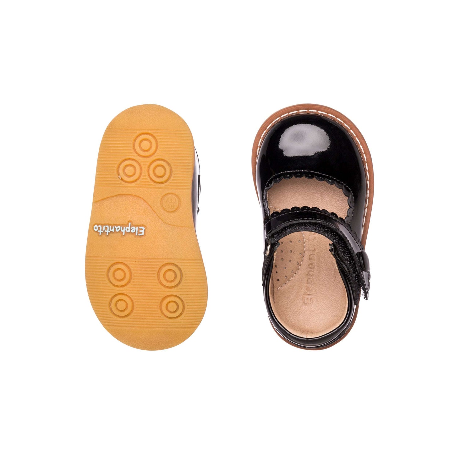 Black patent leather toddler Mary Jane shoe with scalloped edges and tan rubber sole with circular grips.