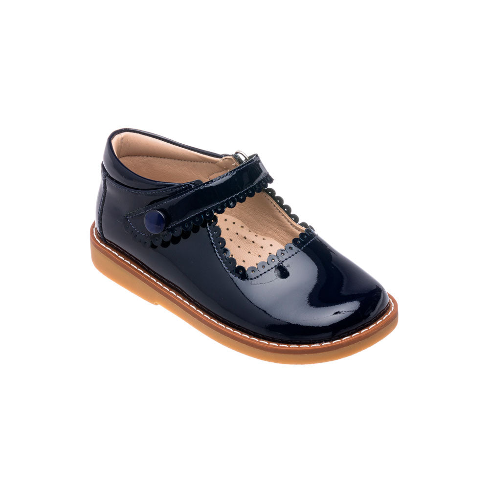 Navy blue patent leather Mary Jane shoe with scalloped strap and tan sole for girls.