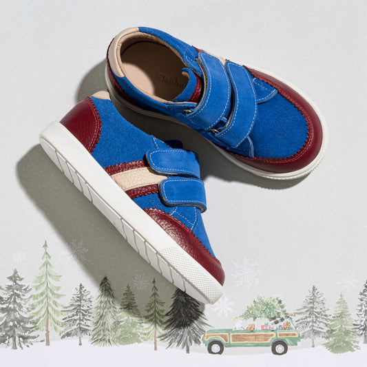 Blue denim boys sneaker with burgundy accents, beige stripe, and white sole, featuring double Velcro straps.