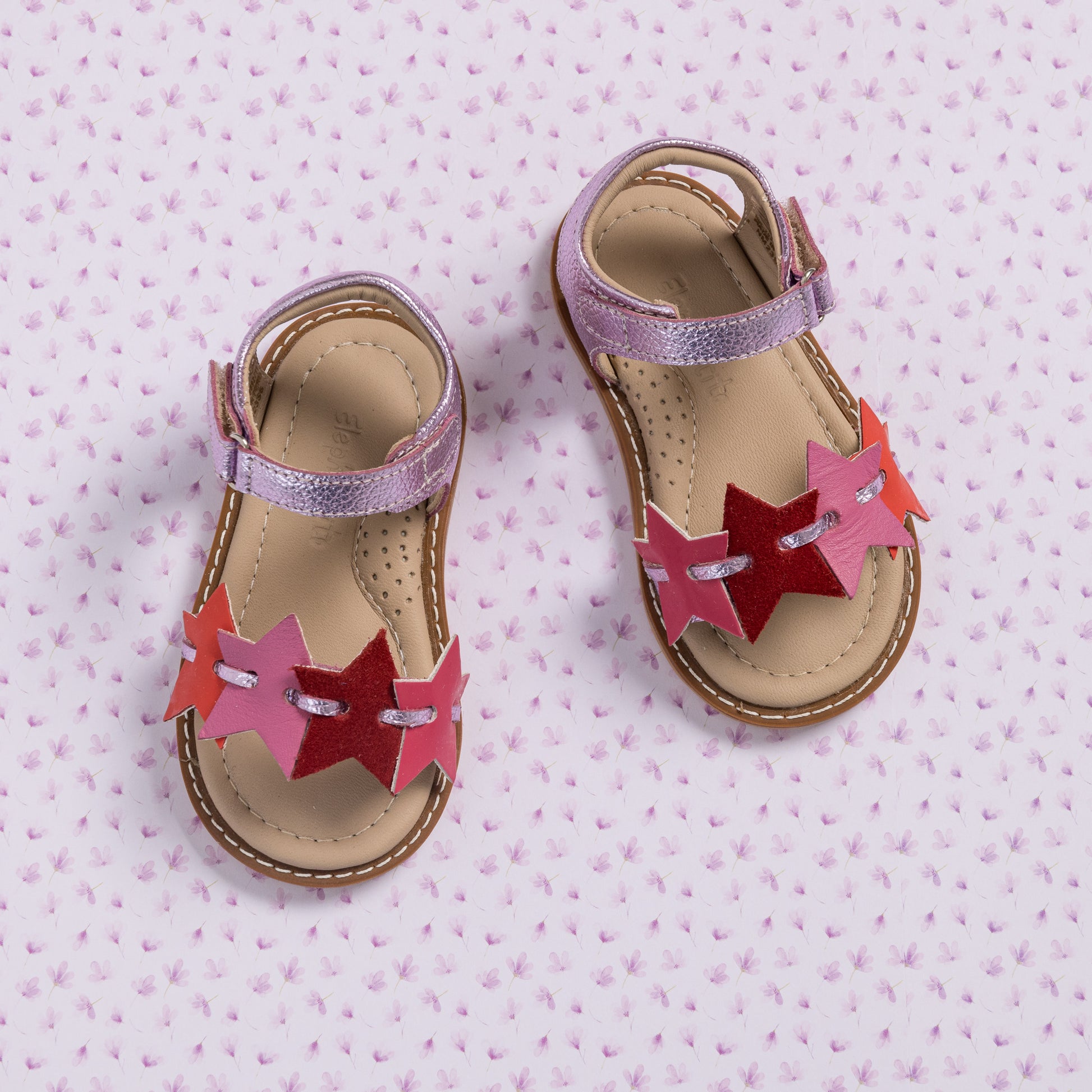 Toddler sandals in fuchsia and pink with star-shaped cutouts and adjustable ankle straps.