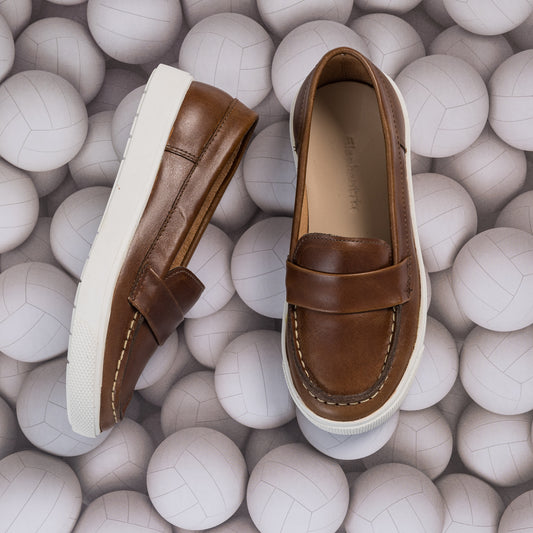 Brown leather boys' loafers with white rubber soles and moccasin-style stitching.