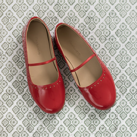 Red leather children's ballerina flats with a thin strap and decorative perforations on toes.
