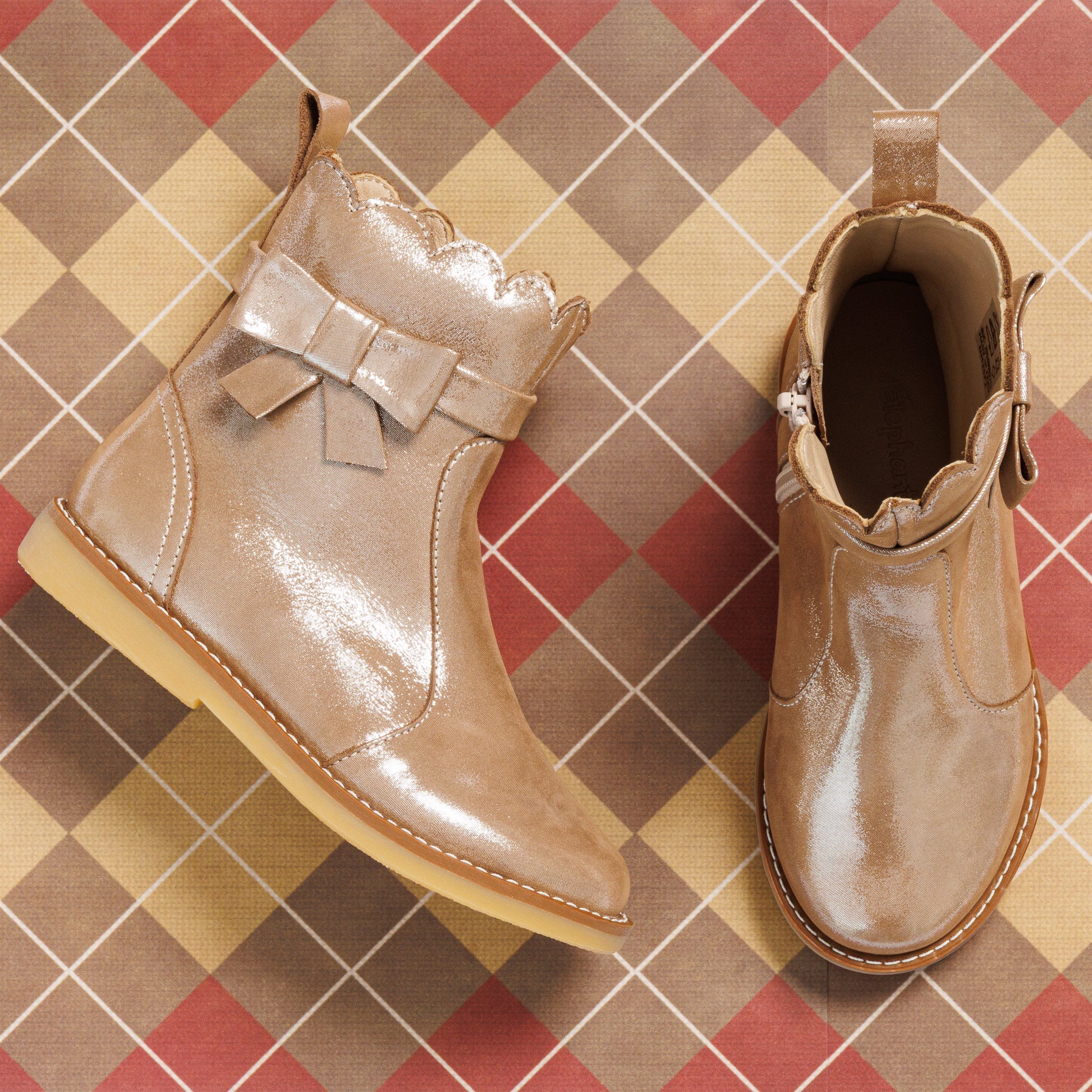 Glossy blush pink toddler booties with scalloped edges and decorative side bows on tan sole.