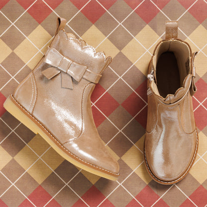 Glossy blush pink toddler booties with scalloped edges and decorative side bows on tan sole.