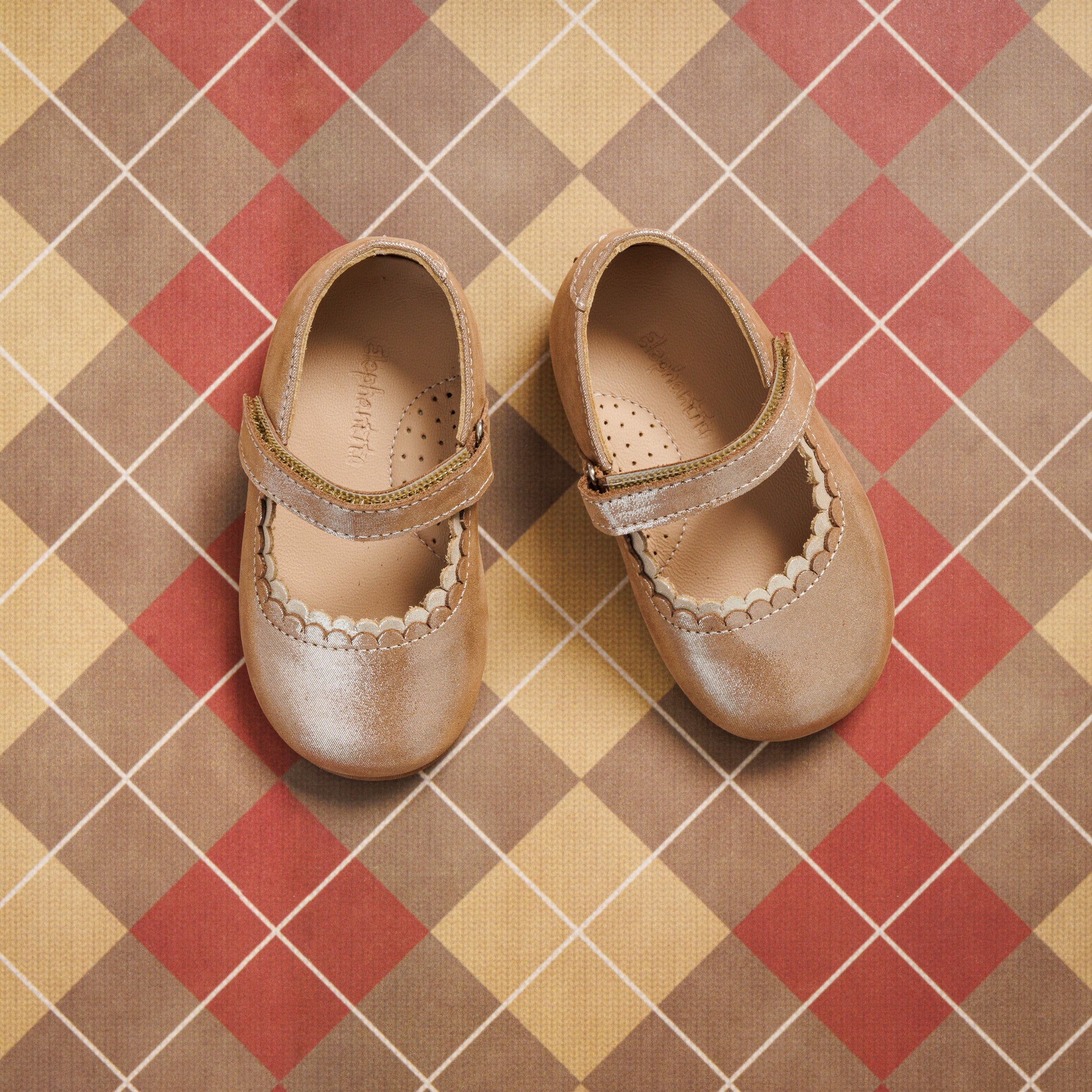 Blush pink toddler Mary Jane shoes with scalloped edge and velcro strap on plaid background.
