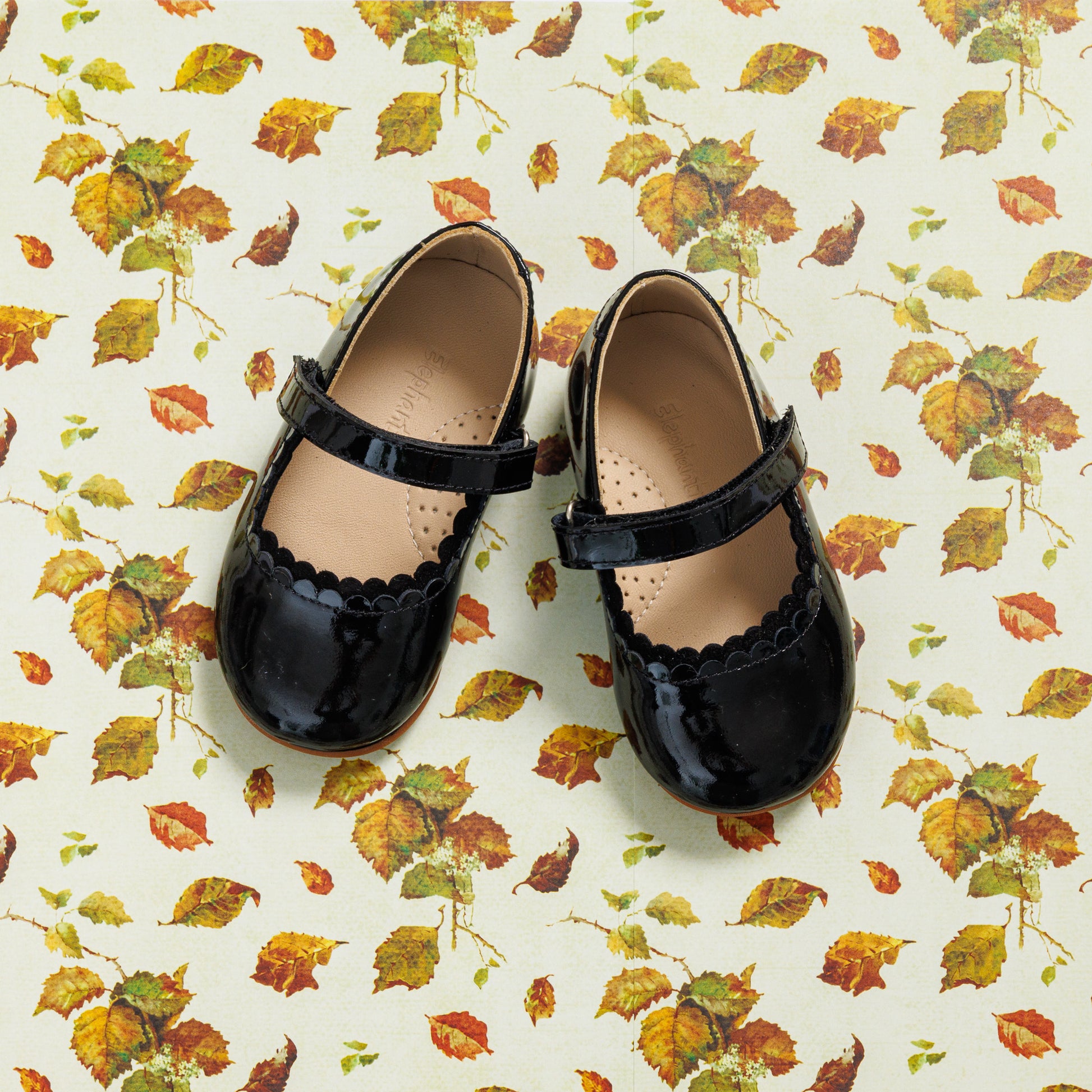 Black patent leather toddler Mary Jane shoes with scalloped edges and a Velcro strap.