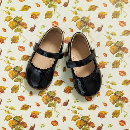 Black patent leather toddler Mary Jane shoes with scalloped edges and a Velcro strap.