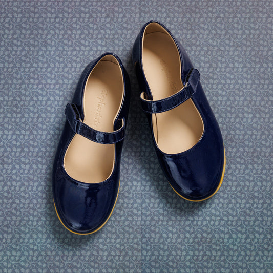 Glossy navy blue patent leather girls Mary Jane shoes with single Velcro strap and tan sole lining.