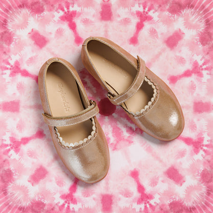 Pink blush toddler girls' Mary Jane shoes with scalloped trim and adjustable strap on tie-dye background.