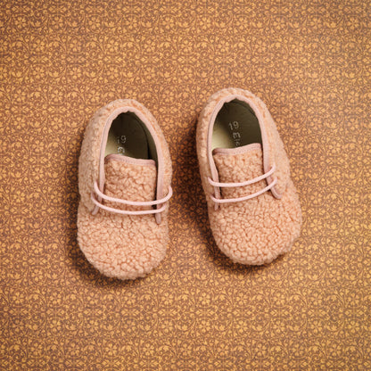 Pink shearling baby booties with soft fuzzy texture and slip-on design.