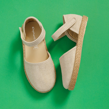 Elephantito - Beige linen espadrille sandals for girls with ankle straps and woven rope soles on green background.