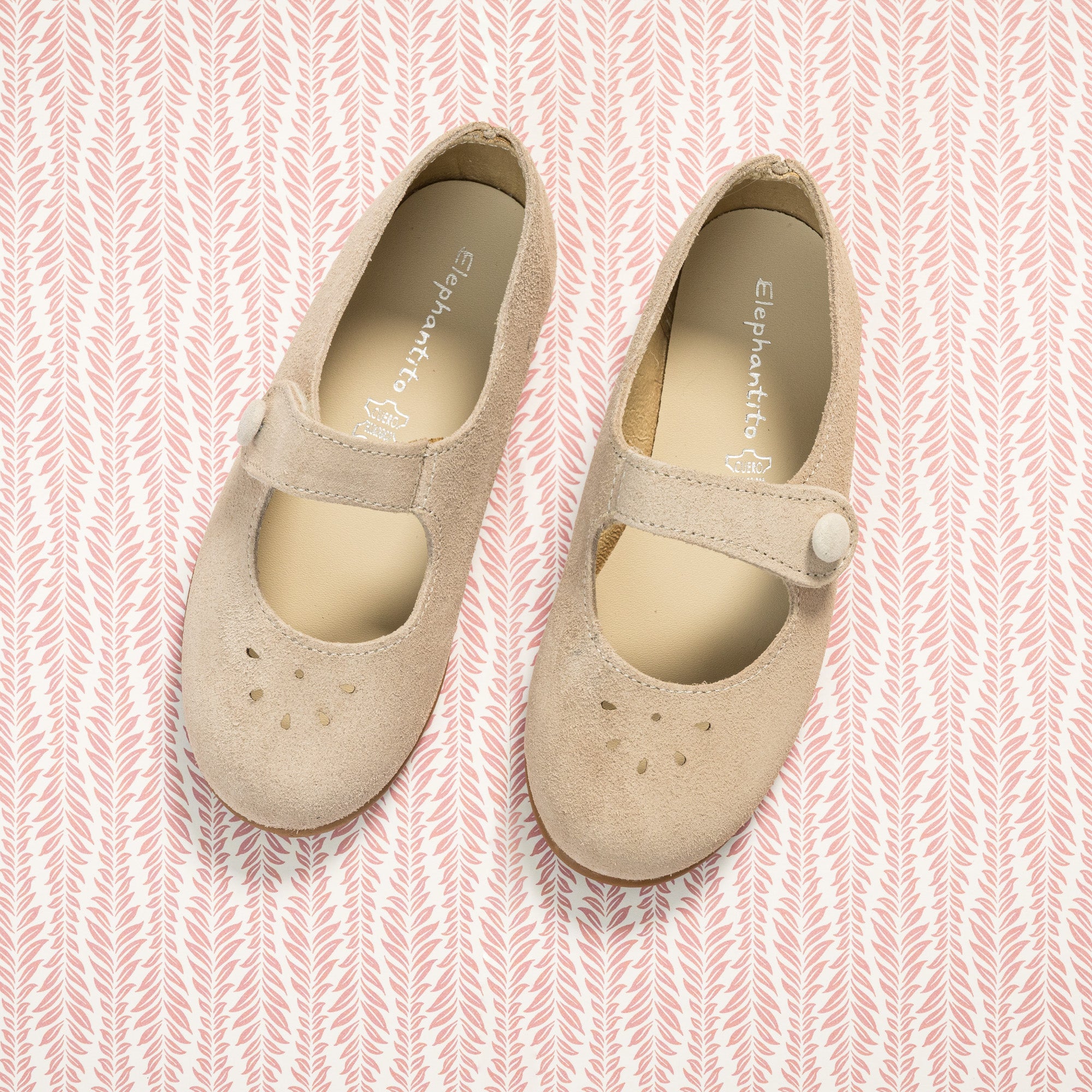 Beige suede Mary Jane shoes for toddlers with button strap and perforated toe design.
