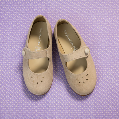 Beige suede Mary Jane shoes for toddlers with button strap and perforated toe design on purple patterned background.