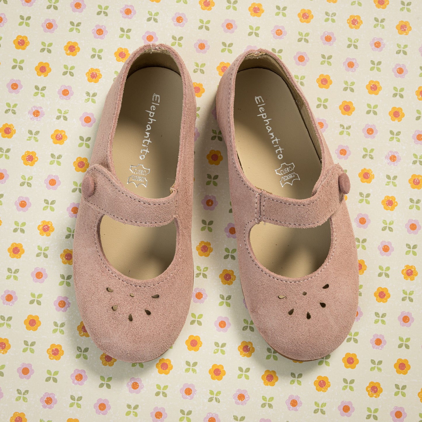 Pink suede Mary Jane shoes for toddlers with scalloped edges and perforated flower details.