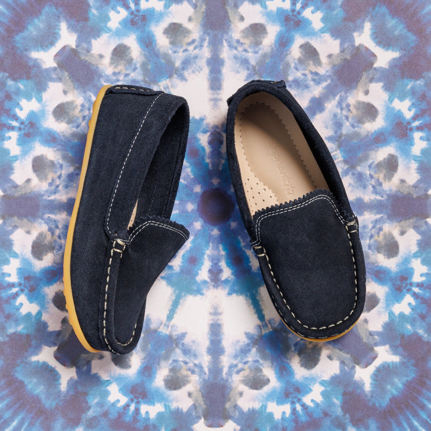 Navy blue suede toddler moccasins with contrast white stitching and tan rubber soles.