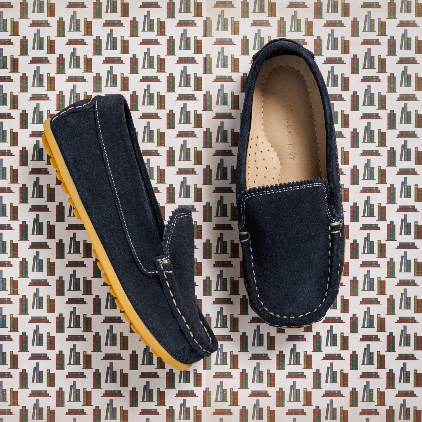 Children's navy blue suede moccasin shoes with tan rubber soles and detailed stitching.