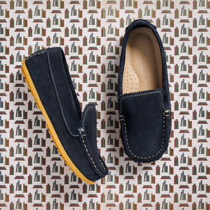 Children's navy blue suede moccasin shoes with tan rubber soles and detailed stitching.