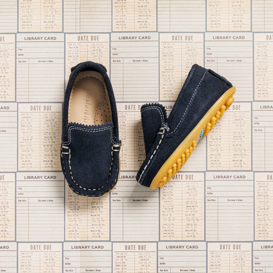 Toddler moccasin driver shoes in navy blue suede with yellow rubber nubs on sole.