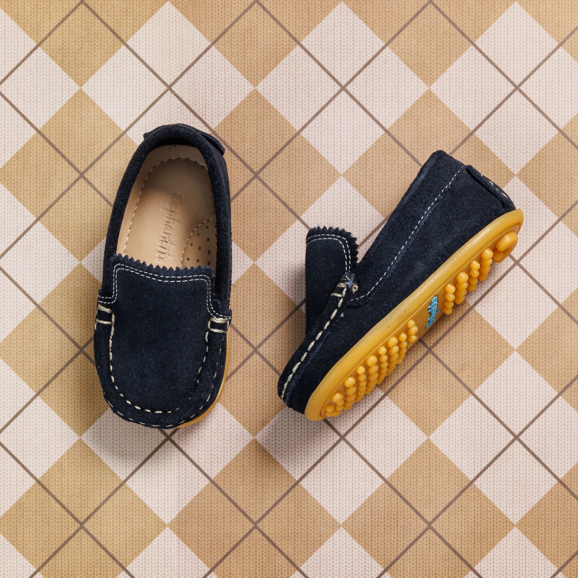 Blue suede toddler moccasin shoes with tan rubber soles and contrast white stitching.