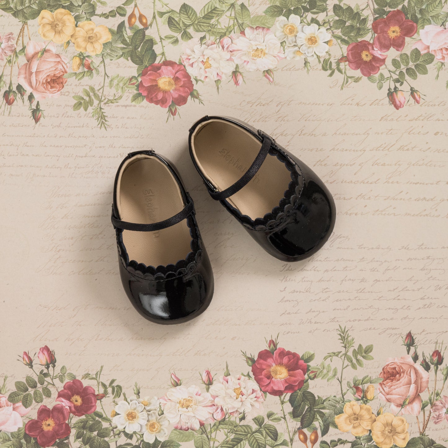 Glossy black patent baby ballet flats with scalloped edges and a single strap across the top.