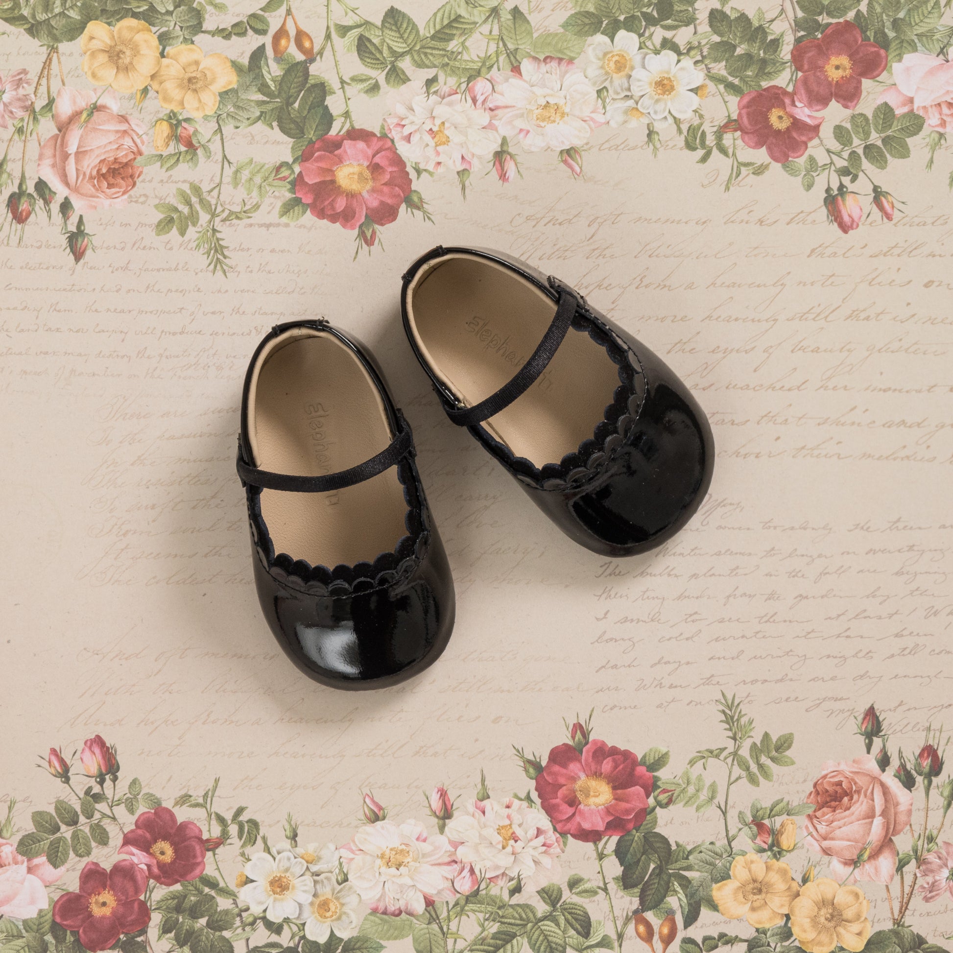 Glossy black patent baby ballet flats with scalloped edges and a single strap across the top.