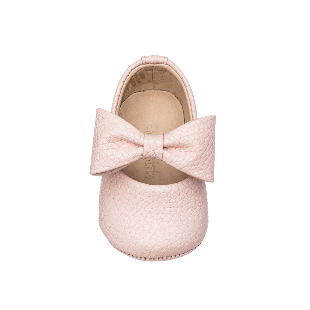 Pink textured leather baby shoe with large bow on top, rounded toe, soft sole.
