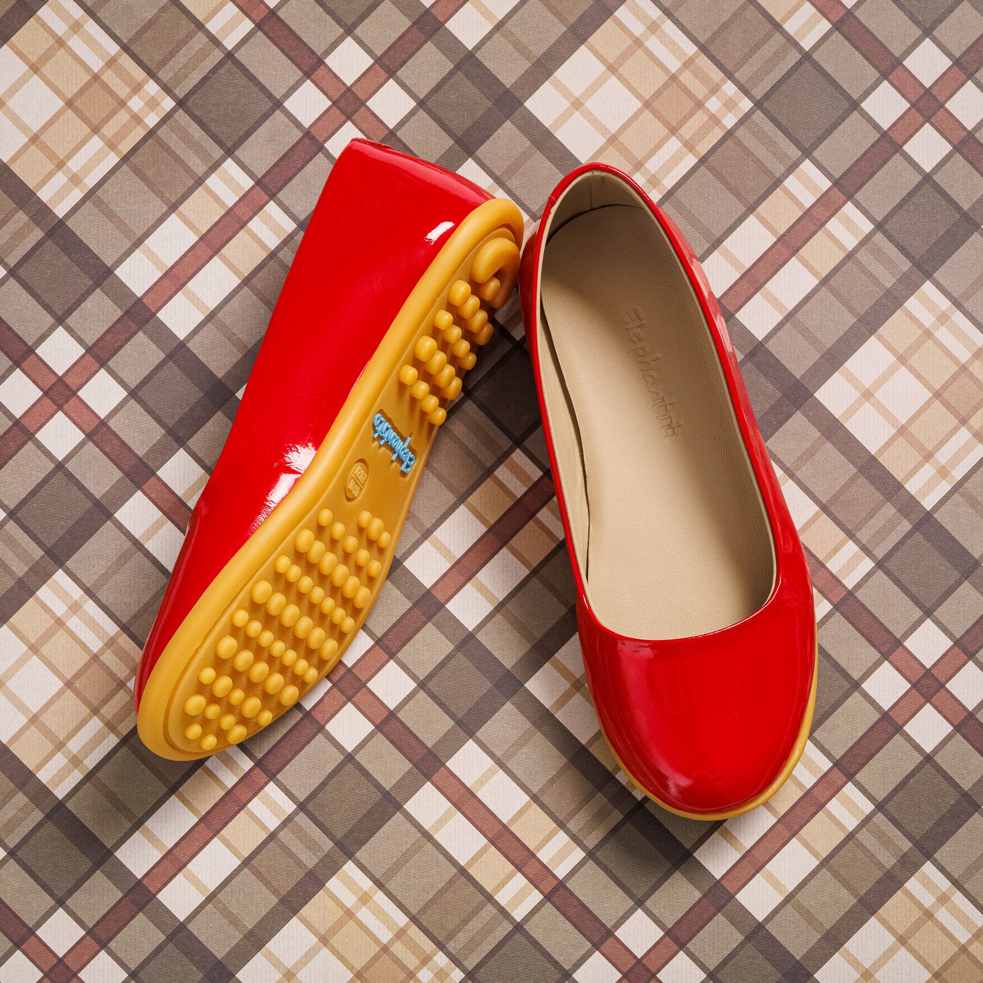 Red patent leather toddler ballerina flats with beige interior and textured yellow rubber sole.