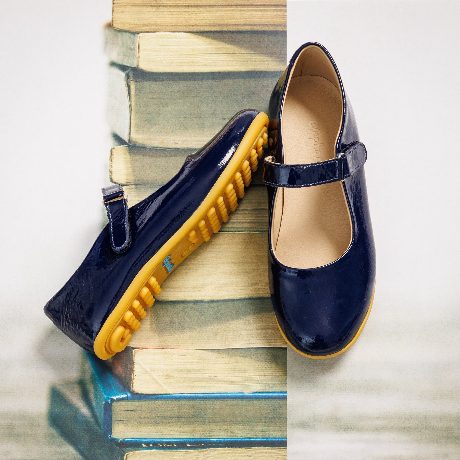 Navy blue girls' Mary Jane shoes with glossy finish and yellow rubber soles, adjustable strap closure.