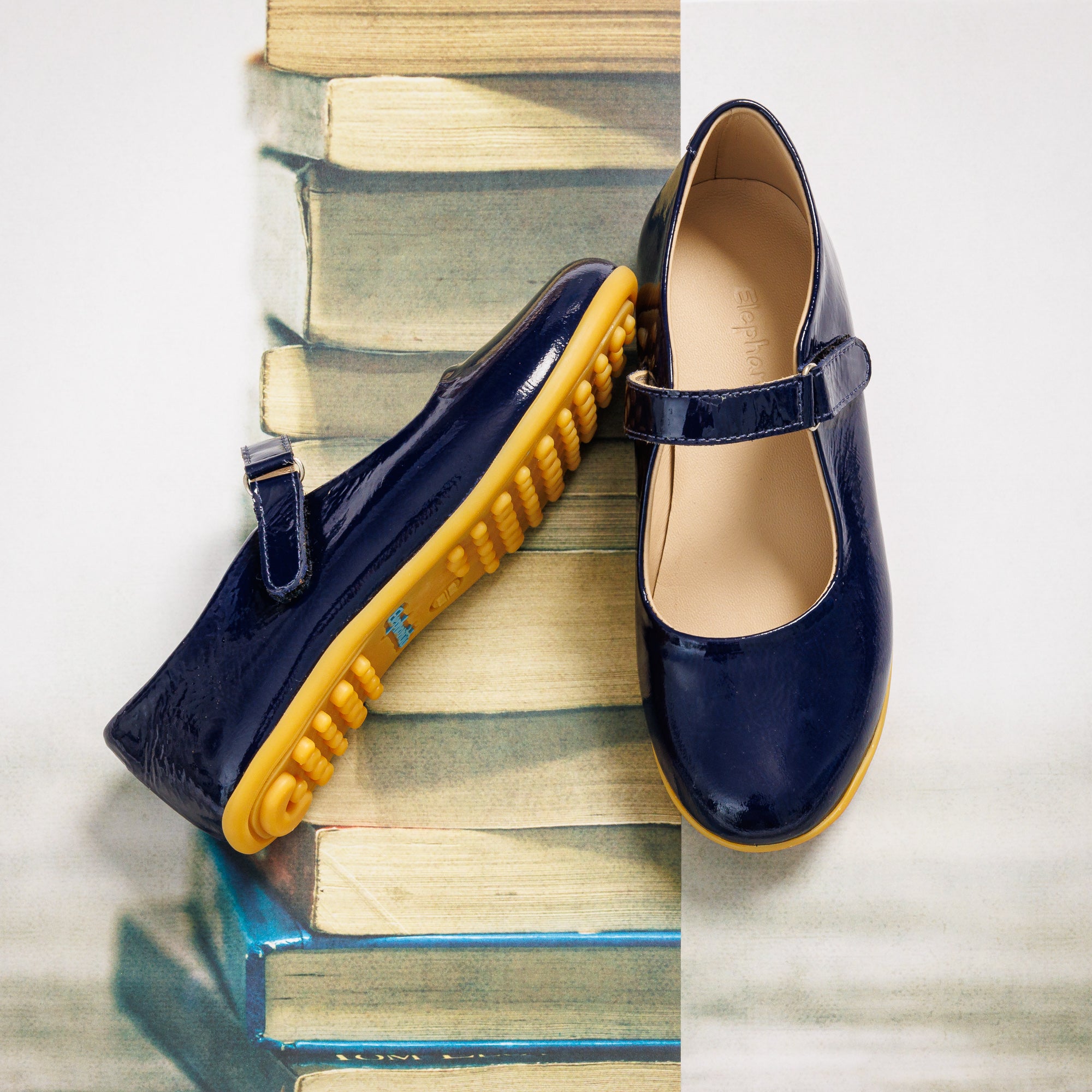 Navy blue girls' Mary Jane shoes with glossy finish and yellow rubber soles, adjustable strap closure.