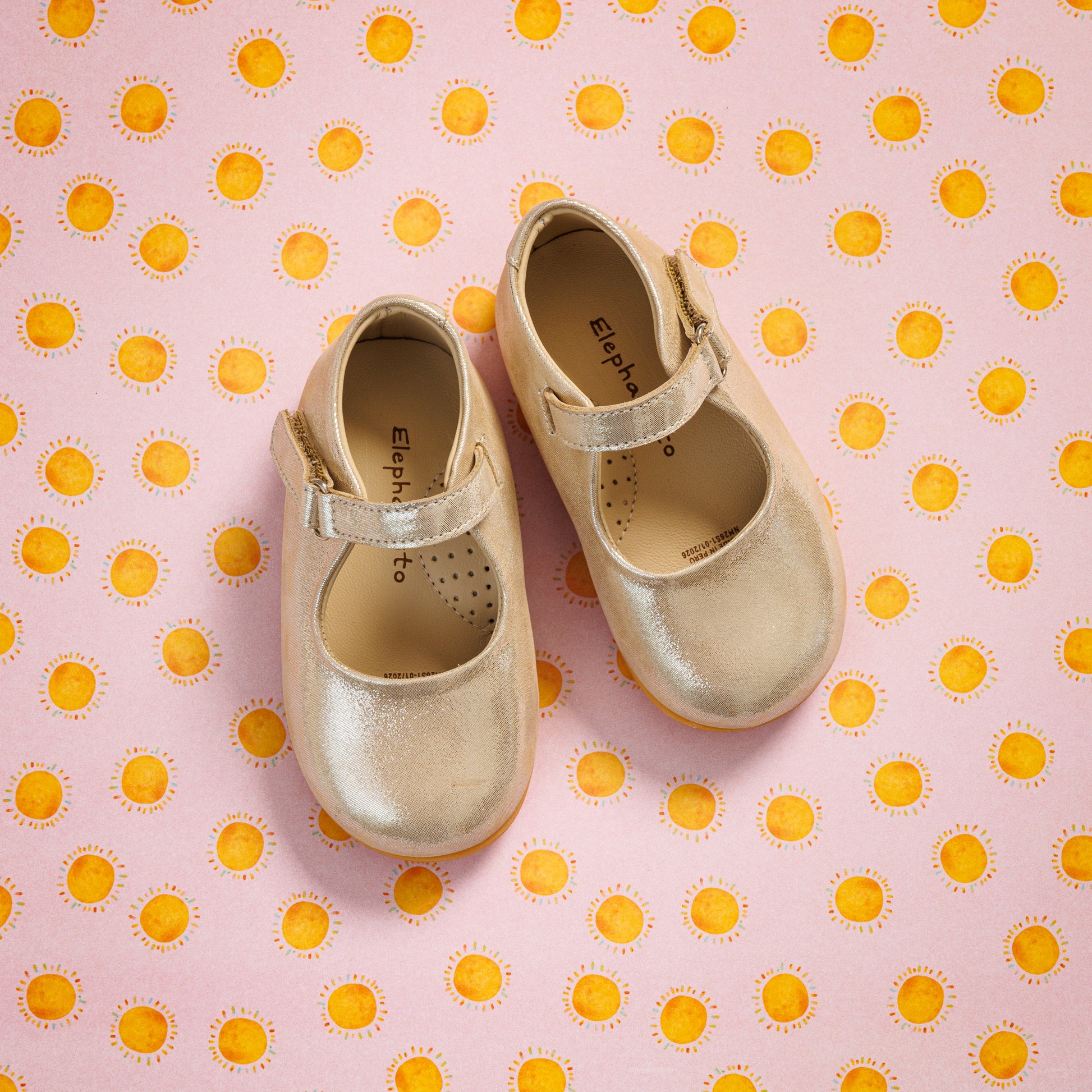 Elephantito - Creamy beige toddler Mary Jane shoes with a single strap, subtle perforated details, on pink polka-dot background.