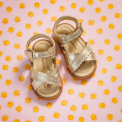 Elephantito - Gold toddler sandals with scalloped straps and adjustable ankle closures on polka dot background.