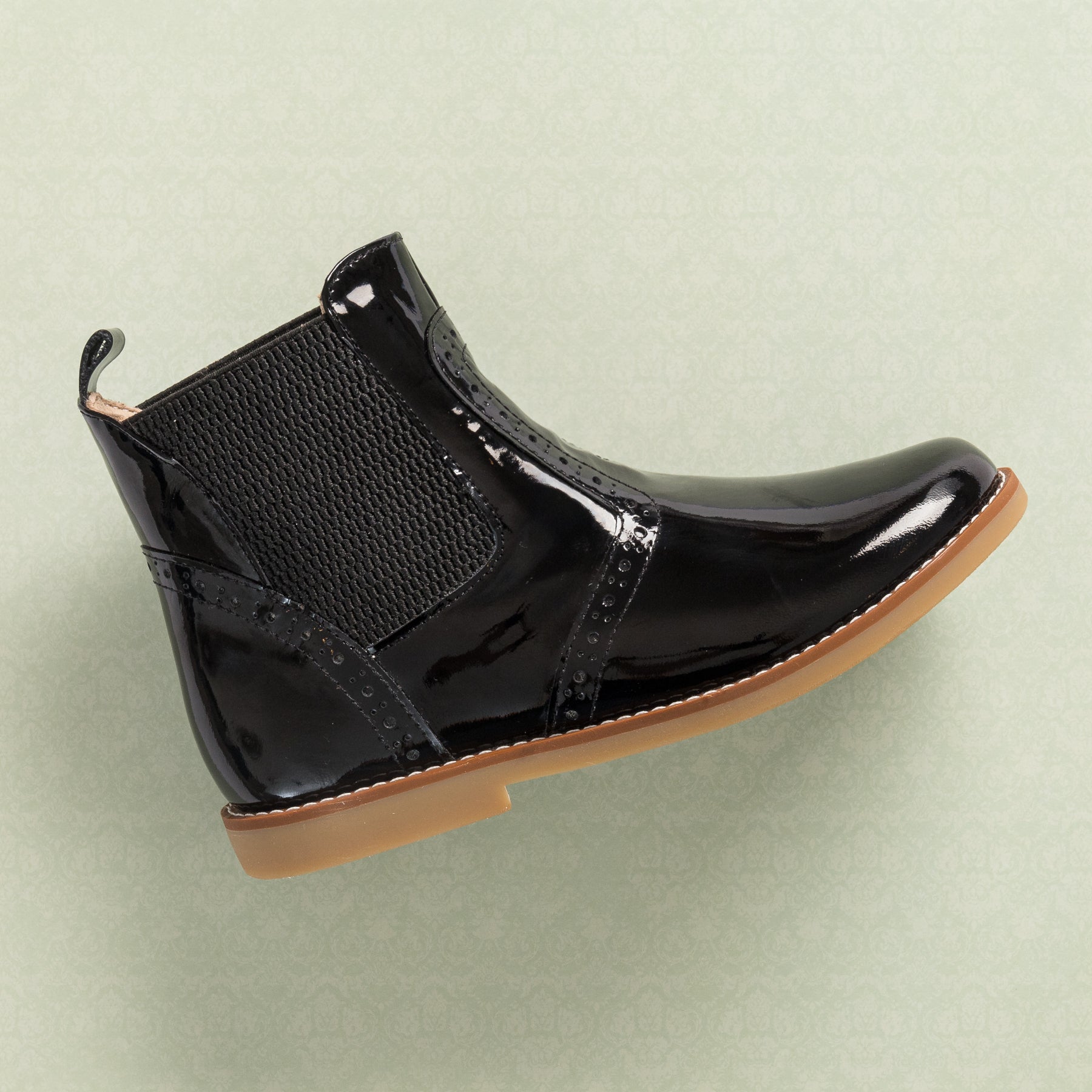 Black patent leather children's bootie with elastic side panels and tan rubber sole.