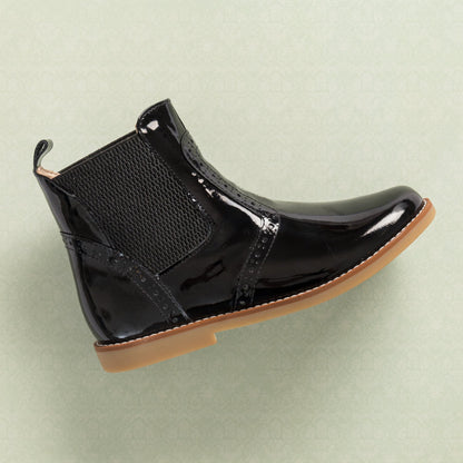Black patent leather children's bootie with elastic side panels and tan rubber sole.