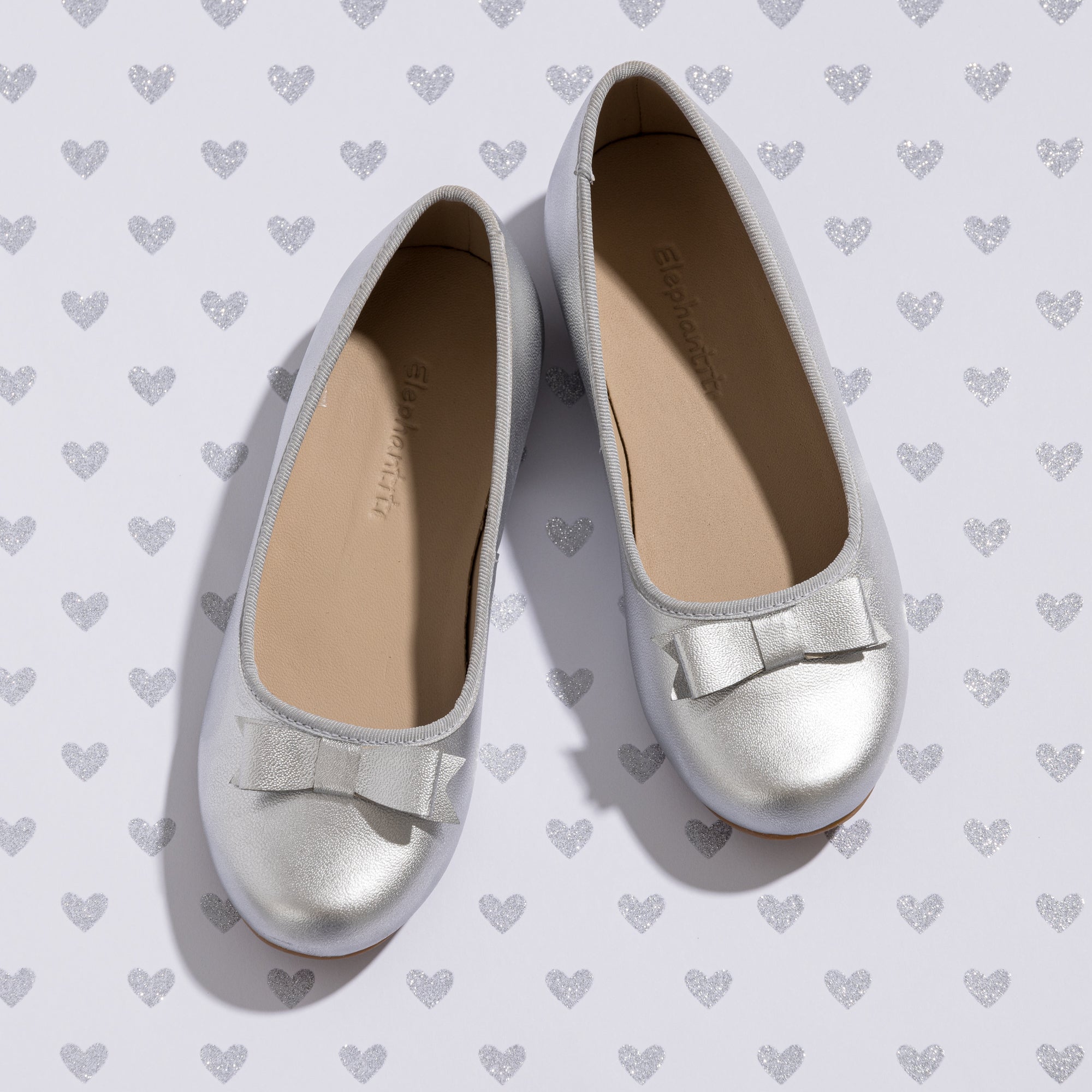 Silver toddler ballerina flats with small matching bow on toe, cushioned beige insole.