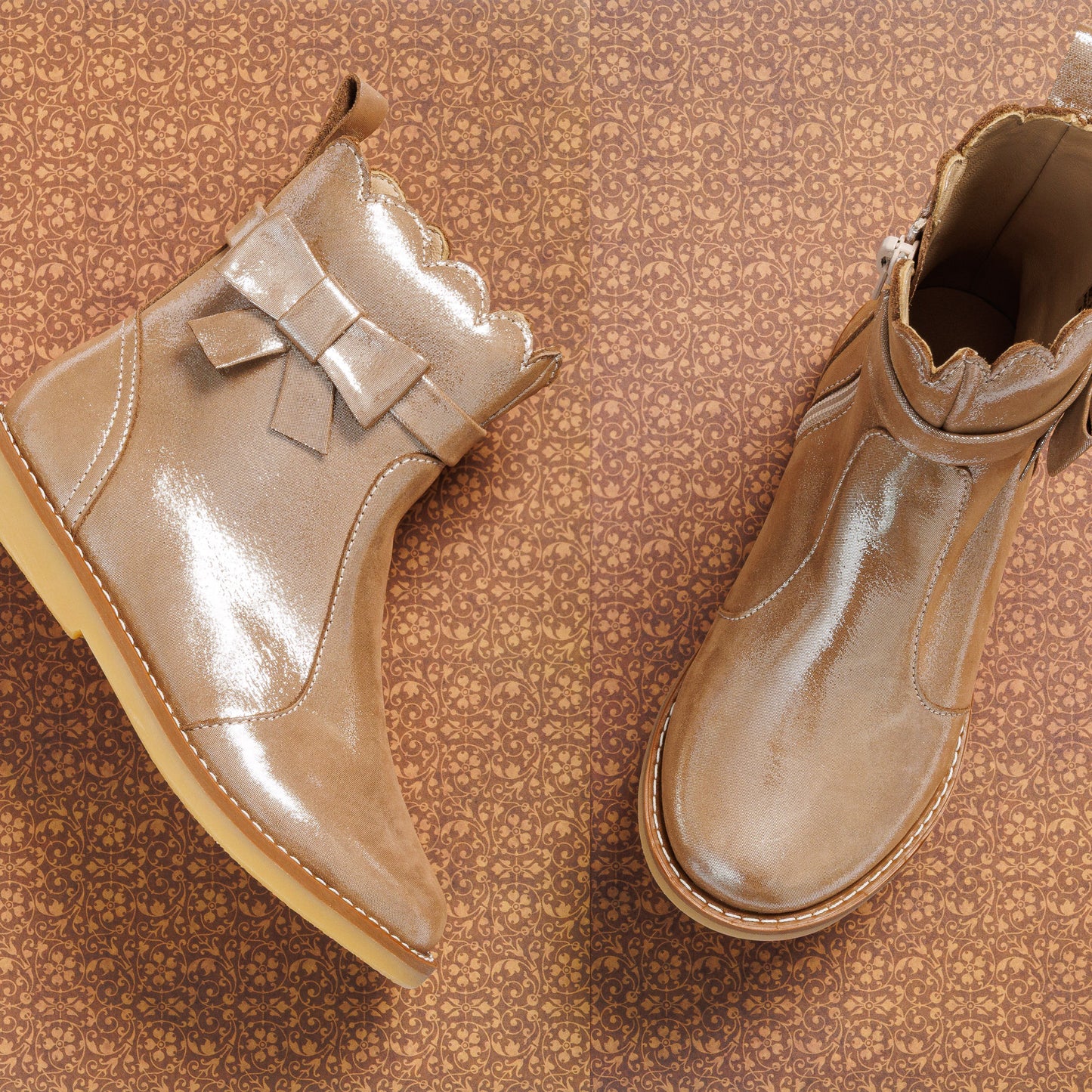 Shiny blush pink toddler booties with scalloped top edge and decorative bow on the side.