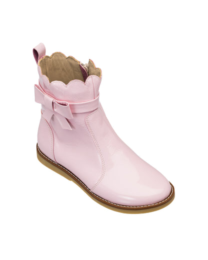 Pink glossy toddler bootie with scalloped top edge and decorative bow on side, tan sole.