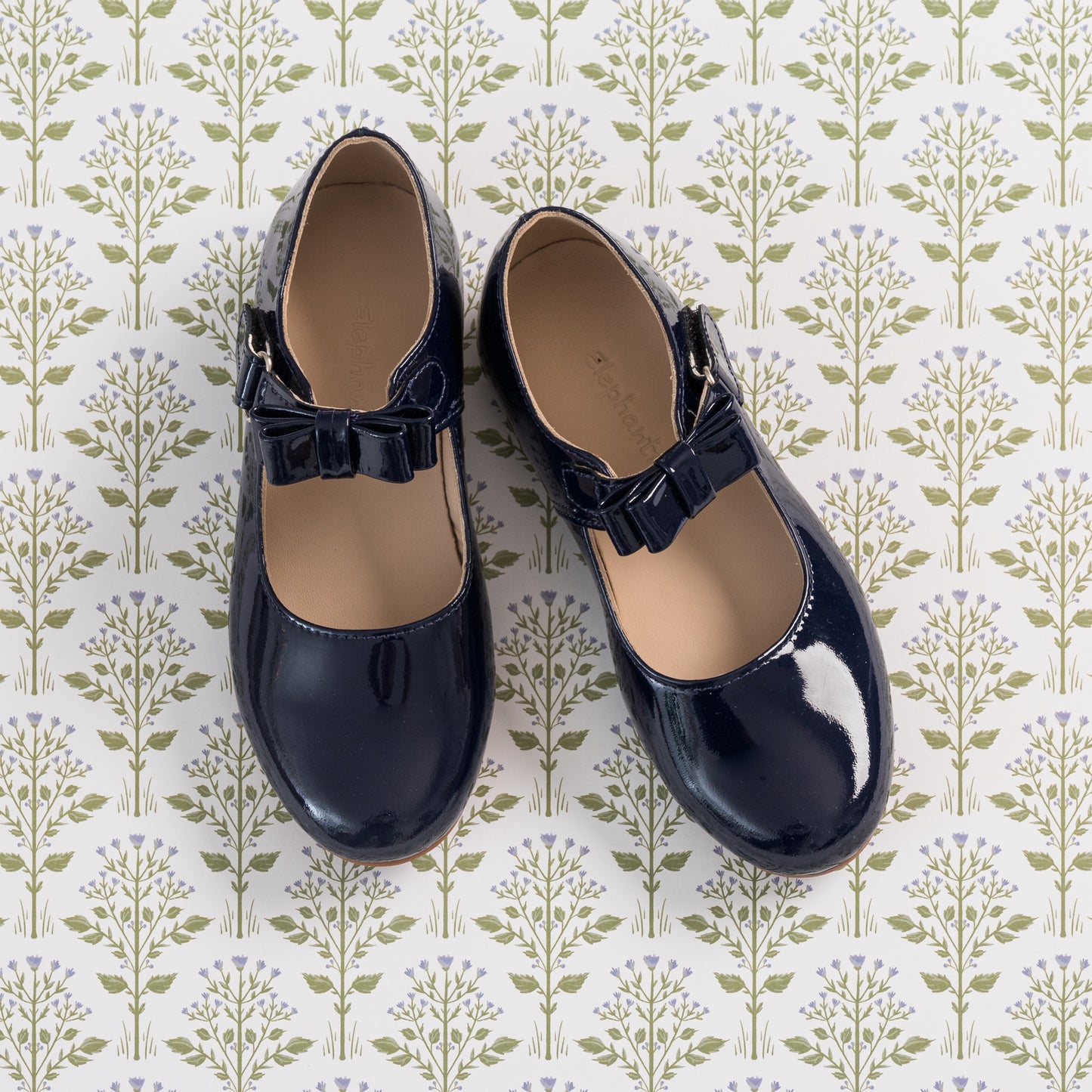 Shiny navy blue toddler Mary Jane shoes with scalloped edges and bow detail on strap.