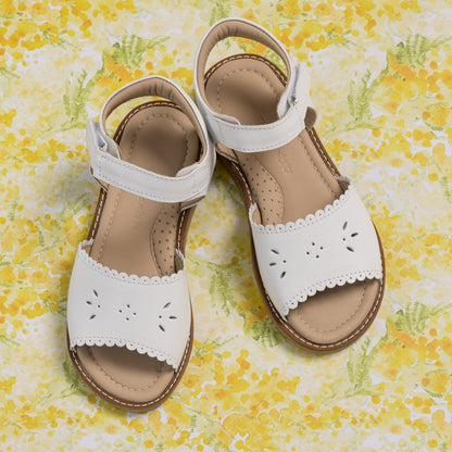 White toddler sandal with scalloped edges and floral cutout on leather upper.