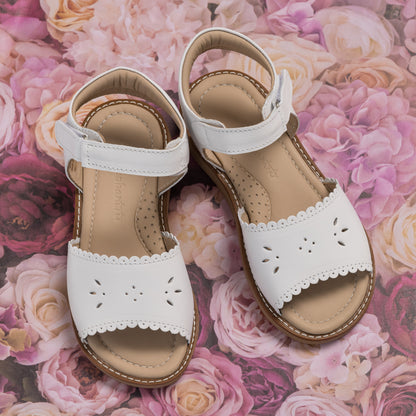 White toddler sandal with scalloped edges and cutout floral details, adjustable back strap.