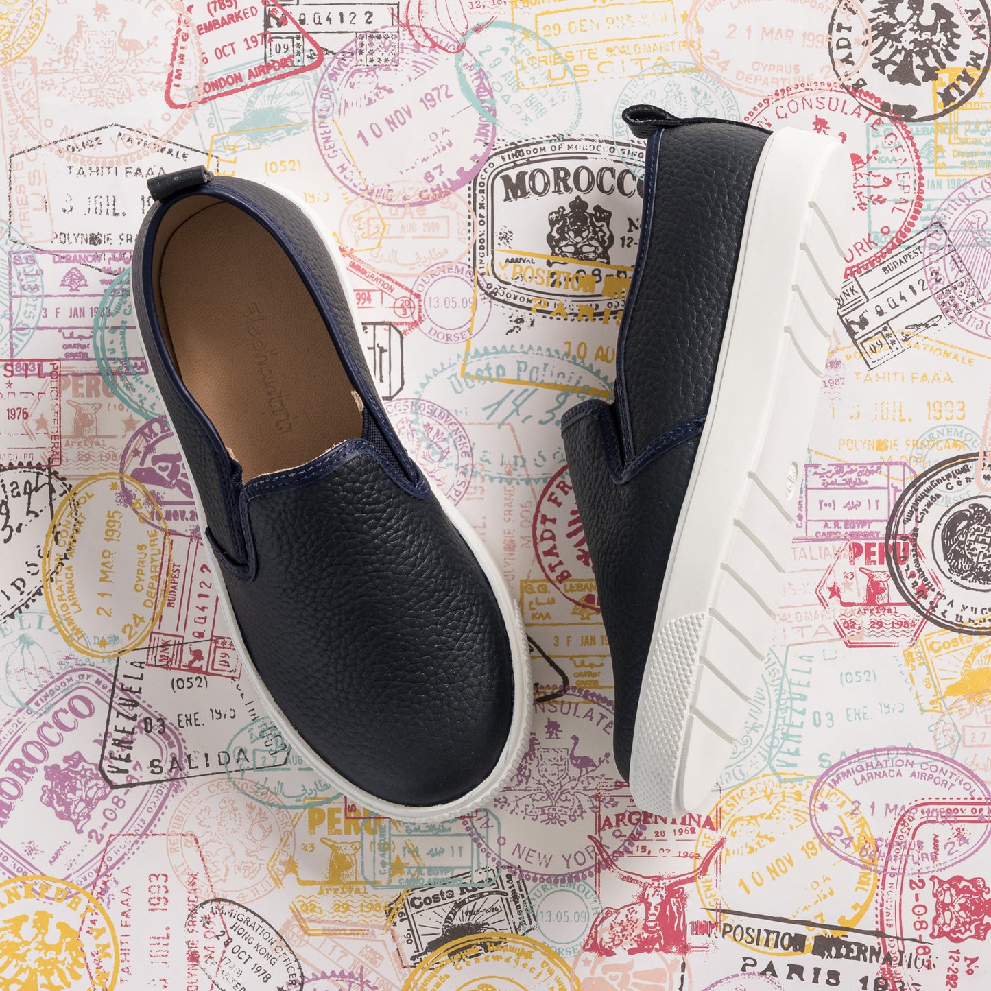 Navy blue textured slip-on shoes for kids with white thick rubber soles and elastic side panels.