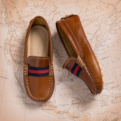 Natural brown leather baby loafer with navy and red striped fabric detail on top.
