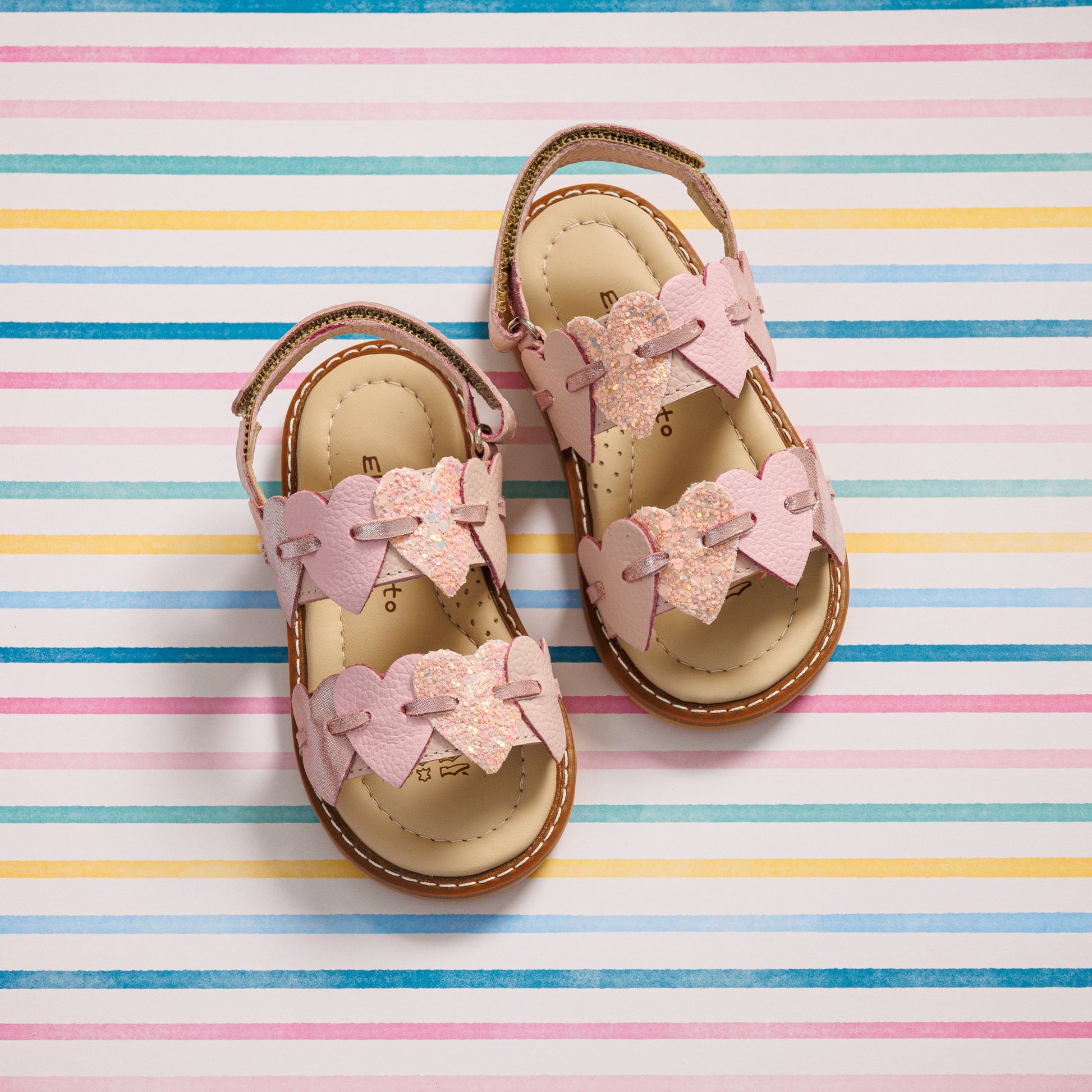 Elephantito - Pink toddler sandals with heart-shaped cutouts and adjustable straps on a striped background.
