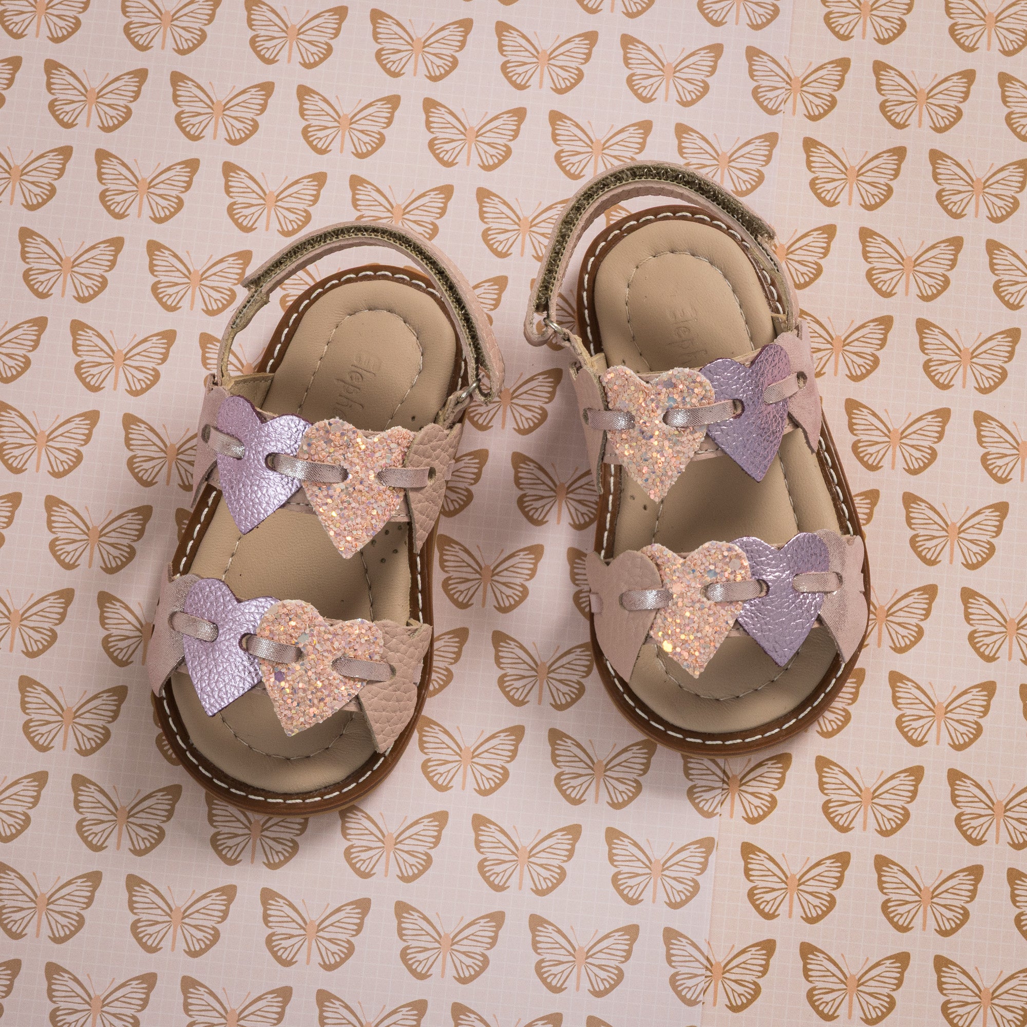 Toddler sandals with pink and lavender butterfly straps on tan footbed and sole.