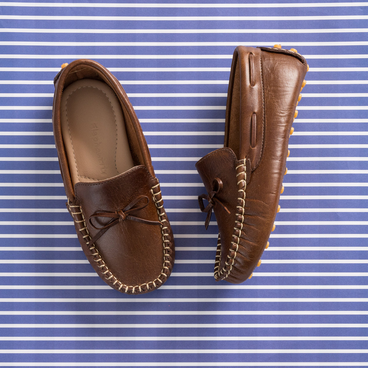 Brown leather driver loafer with stitched trim and decorative bow on top.