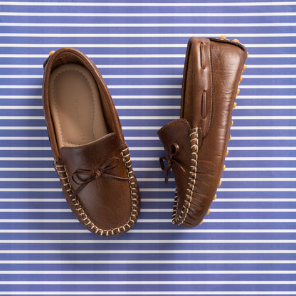 Brown leather driver loafer with stitched trim and decorative bow on top.