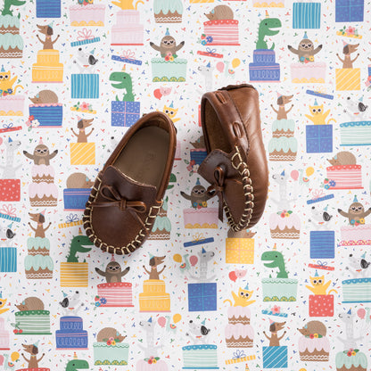 Brown leather baby driver loafers with front bow and woven detailing on rubber sole.