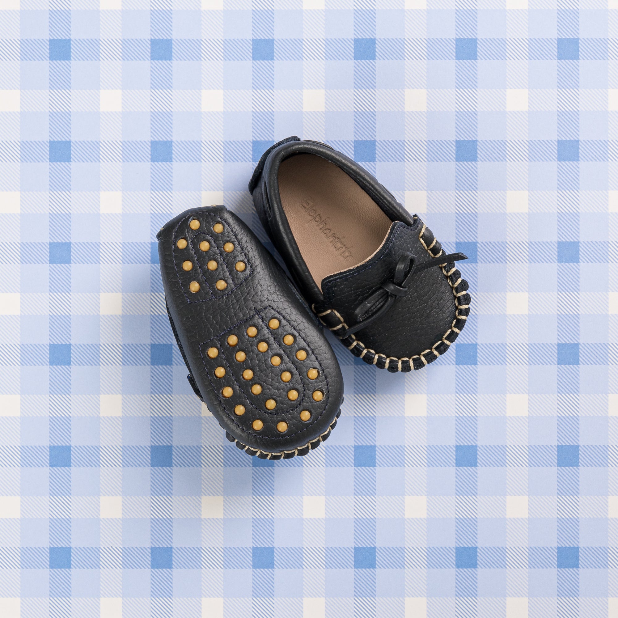 Navy blue baby driver loafers with gold studded soles and stitched detailing.