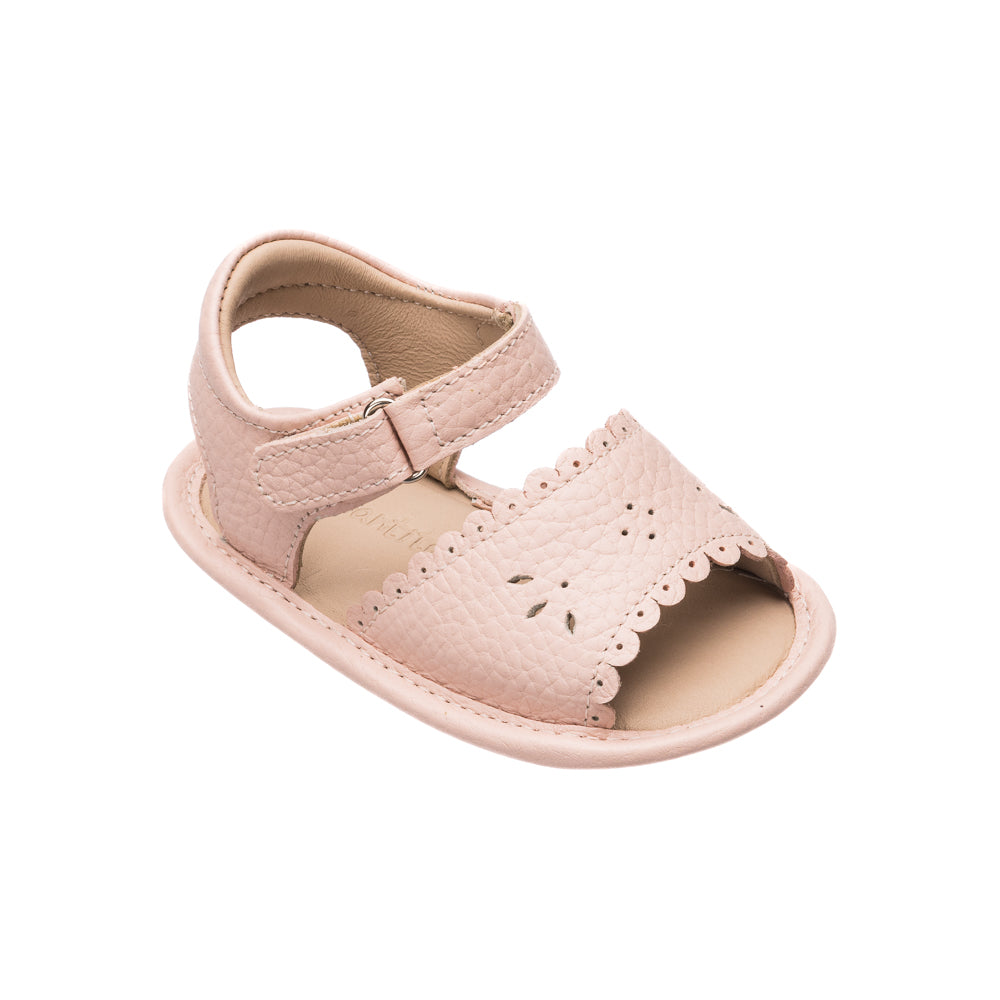 Pink toddler sandal with scalloped edges and perforated floral details, adjustable ankle strap.