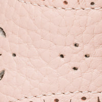 Close-up of soft pink leather with scalloped edges and small perforated details on children's sandal.