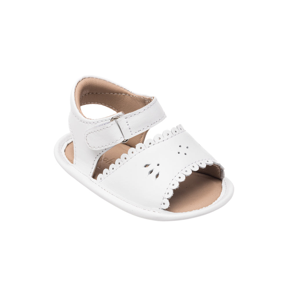 White leather baby sandal with scalloped edges and floral cutout details, adjustable ankle strap.